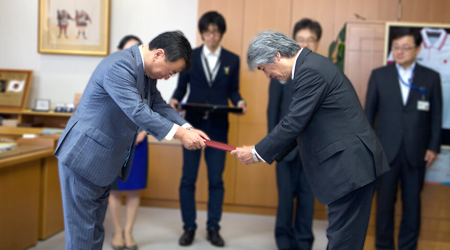 松野文部科学大臣（当時）から指定書を受け取る山極総長イメージ